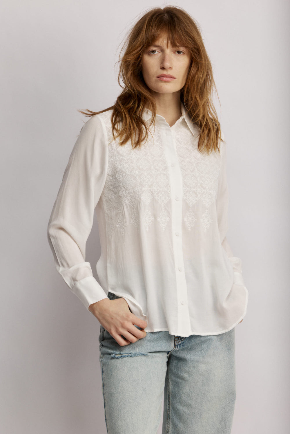 Janice מכופתרת לבנה בגזרה קלאסית בעלת עיטורי רקמה עדינים בחזית. משכית